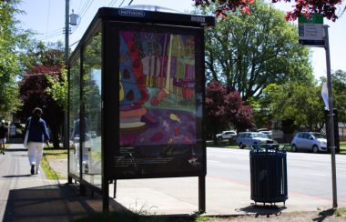 A bright painting is on the side of a bus shelter in Victoria on a sunny day.