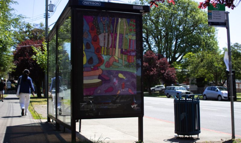 A bright painting is on the side of a bus shelter in Victoria on a sunny day.