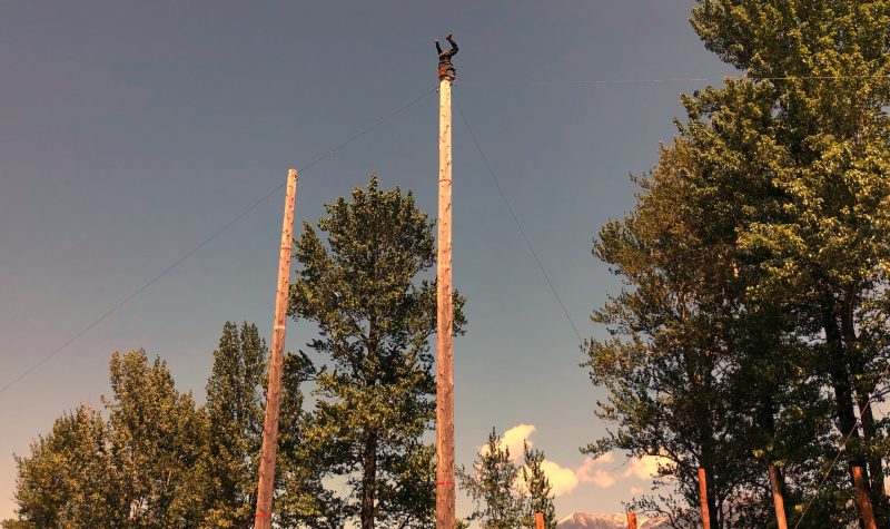 man upside down on top of what looks like a telephone pole