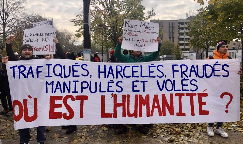 People hold up a banner that reads, 'where is the humanity?' outdoors in a city.