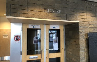 Entrée de la salle de spectacle de La Cité francophone. On aperçoit deux portes en vitres et les inscriptions du mot Théâtre au-dessus sur un mur de brique.