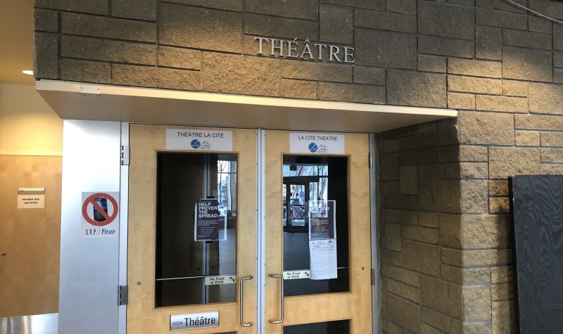 Entrée de la salle de spectacle de La Cité francophone. On aperçoit deux portes en vitres et les inscriptions du mot Théâtre au-dessus sur un mur de brique.