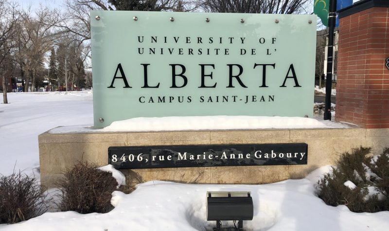 Panneau d'indication du campus Saint-Jean de l'Alberta. Les écritures sont en noires et le panneau est blanc. Le mot Alberta est plus gros en taille que les autres mots. Le panneau indique Université de l'Alberta Campus Saint-Jean.