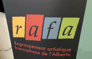 Affiche du Regroupement artistique de l'Alberta. L'affiche est de couleur noire et un carré encadre chaque lettre du nom. La lettre R est encadré d'un carré jaune, la lettre a est encadré d'un carré rouge, la lettre F est encadré en bleu et l'autre lettre A est encadré en vert.