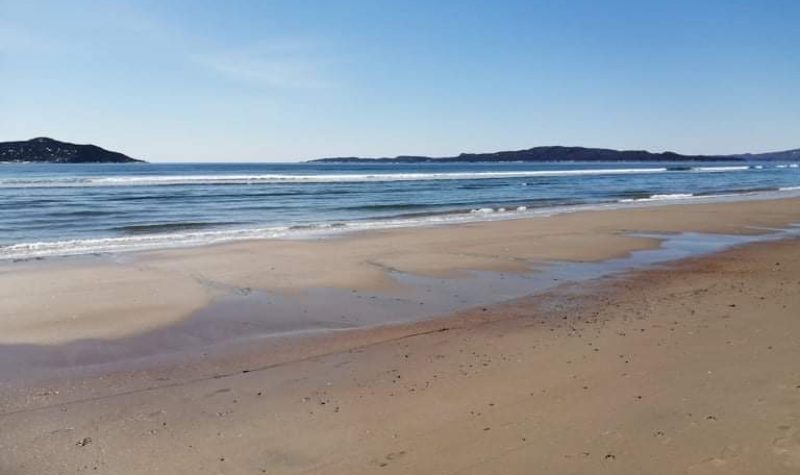 Une plage à marée basse avec au loin deux îles.