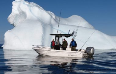 Un bateau sur l'eau avec trois personnes à son bord, devant un iceberg trois fois sa taille.