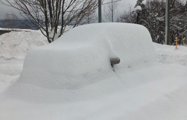 A vehicle completely covered in snow with the only the mirrors showing.