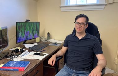 Photo of Dalhousie University economics assistant professor in his office smiling.