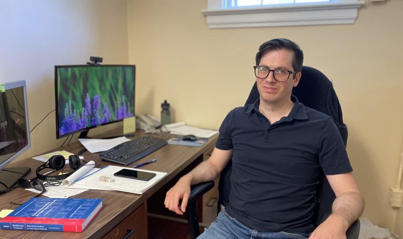 Photo of Dalhousie University economics assistant professor in his office smiling.