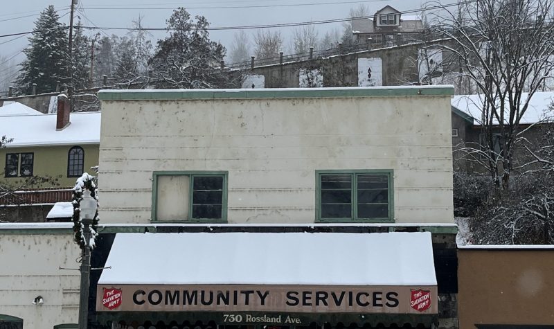 Old building with awning covered in snow. Awning reads community services with Salvation Army logos.