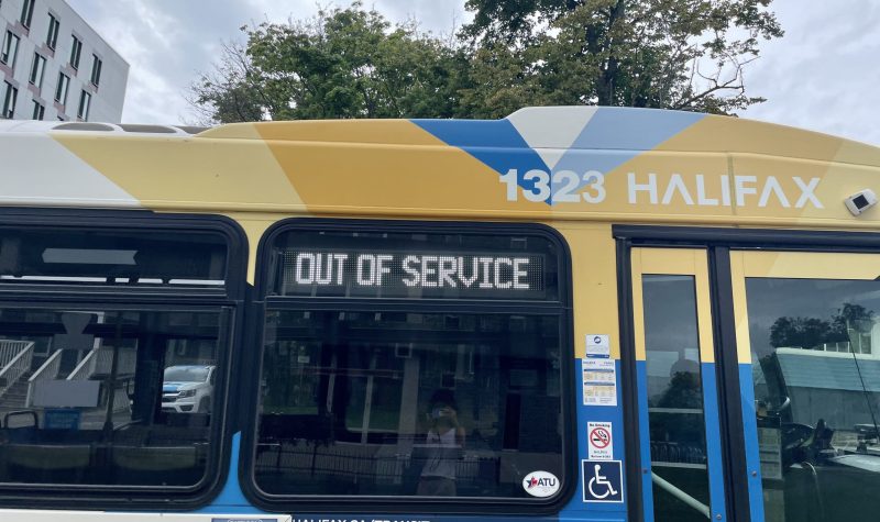 A blue, yellow and white Halifax transit city bus with a sign that says out of service.