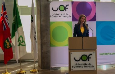 Ministre debout devant des drapeaux de l'Ontario Français et de la province