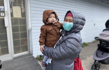 A mother and her infant child standing in line for a coat drive at Parkers Street food and furniture bank.