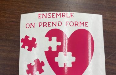 autocollant avec un coeur rose géant et des pièces de puzzle lui permettant de prendre forme. Avec l'inscription : Ensemble on prend forme.