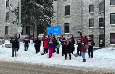 People with signs gather outside of Kingston General Hopsital on a snowy day to protest and rally for better care, staffing and wages for nurses.