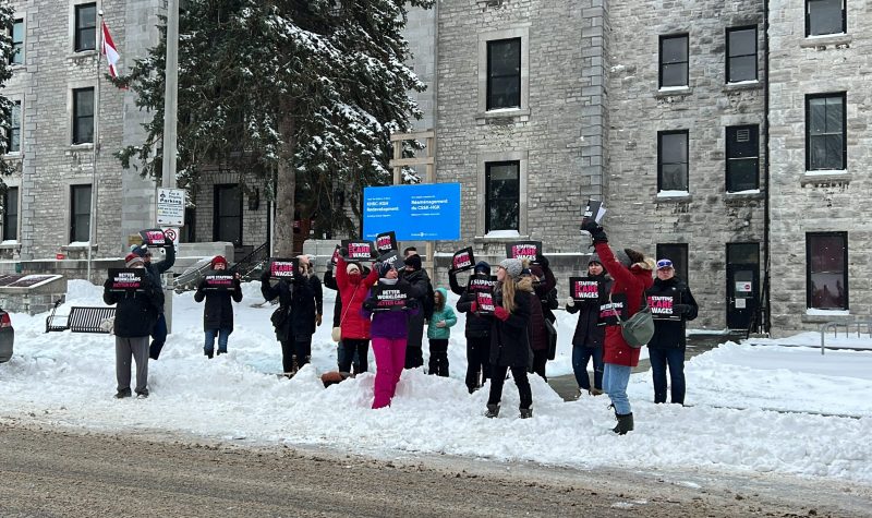 People with signs gather outside of Kingston General Hopsital on a snowy day to protest and rally for better care, staffing and wages for nurses.