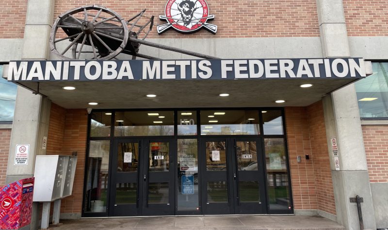 L'immeuble est brun et porte une enseigne en lettres blanches indiquant le nom de la Fédération des Métis du Manitoba.
