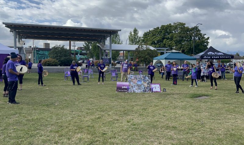 group of cultural drummers in a cercle drumming outdoors in a park wearing purple