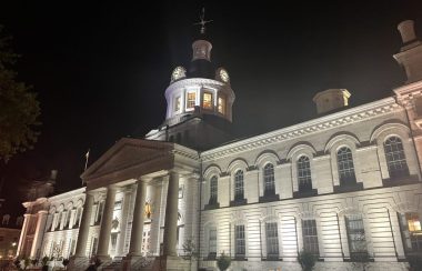 City Hall in Kingston, Ontario, the white building illuminated and standing out at st night.