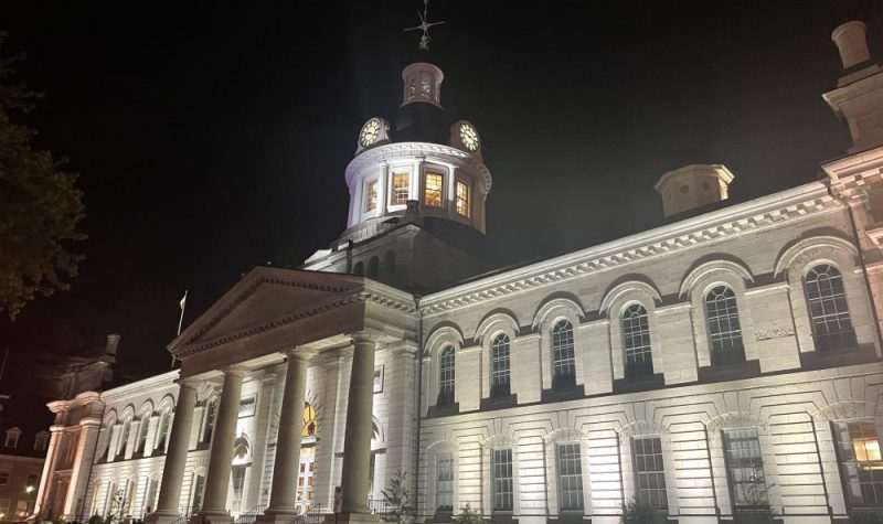 City Hall in Kingston, Ontario, the white building illuminated and standing out at st night.