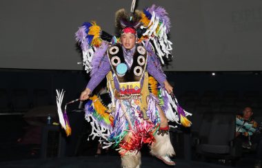 A traditional dancer in full regalia performs a traditional dance. Photo was taken in low-light.
