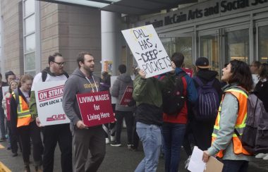 A CUPE 3912 union members forming a picketing line in front of Dalhousie's building. Men and women are seen holding posters asking for wage increases.