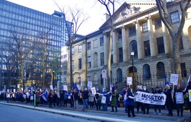 Around 100 people standing in front of the Nova Scotia Legislature. They are holding up signs and posters with NSCEU, ECEs and calls for equal pay.