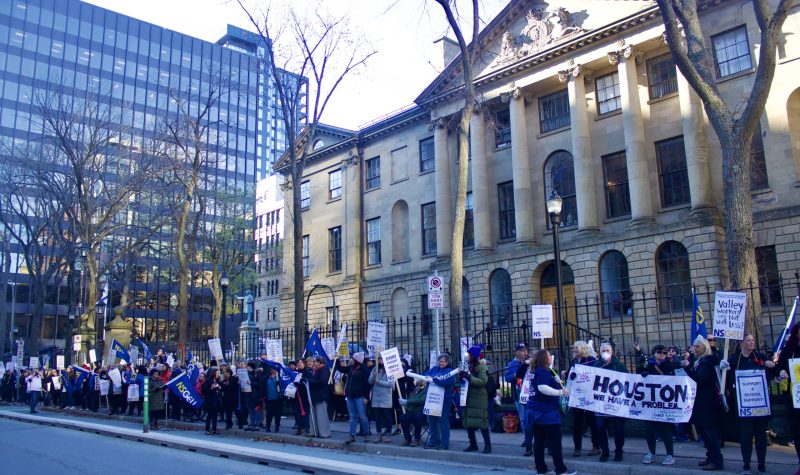 Around 100 people standing in front of the Nova Scotia Legislature. They are holding up signs and posters with NSCEU, ECEs and calls for equal pay.