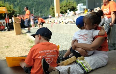 A woman sits with two children at the Indigenous solidarity day in Smithers BC