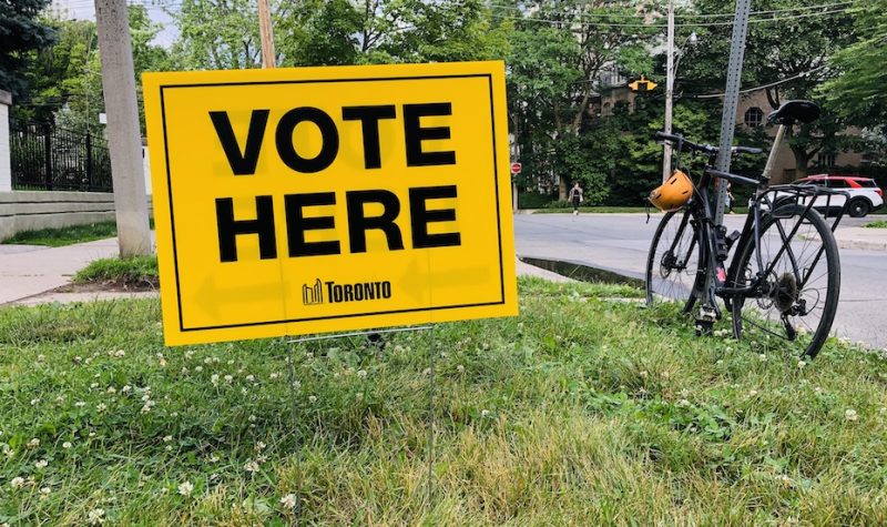 Panneau VOTE HERE jaune, planté sur de l'herbe