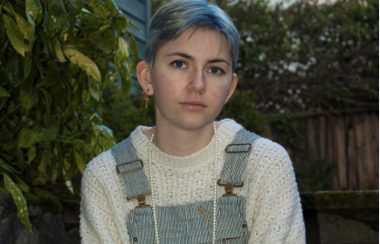 Portrait d'une jeune personne en salopette, cheveux courts aux reflets bleus