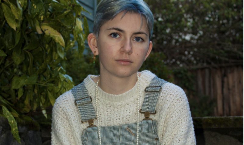 Portrait d'une jeune personne en salopette, cheveux courts aux reflets bleus