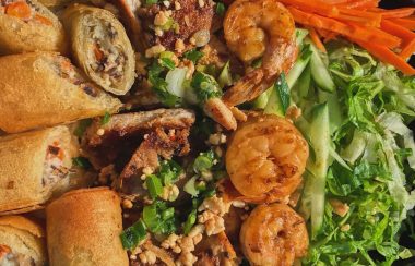 A close up of spring rolls, shrimp, and vegetables.