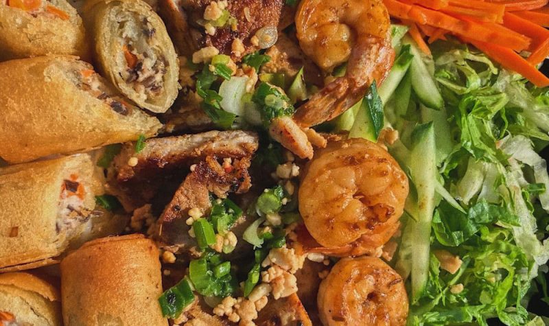 A close up of spring rolls, shrimp, and vegetables.