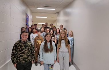 Des enfants de cinquième année pour une photo de groupe dans le corridor d'une école, les murs sont tous blanc