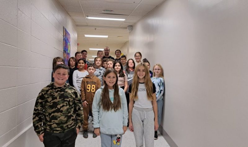 Des enfants de cinquième année pour une photo de groupe dans le corridor d'une école, les murs sont tous blanc