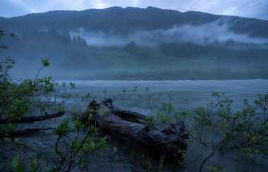 Mist over a river in front of big mountains.