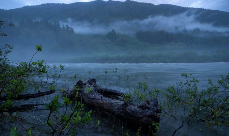 Mist over a river in front of big mountains.
