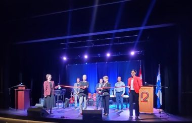 Membres de la création du Pavillon des arts de Forestville avec un ruban rouge dans une salle éclairée de bleu