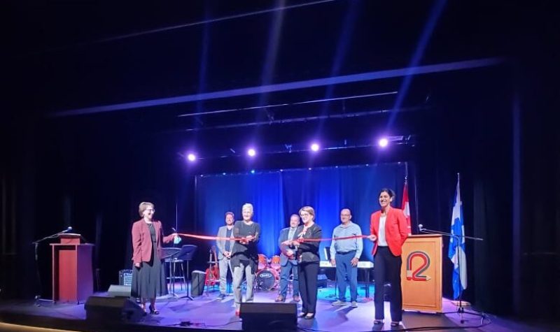 Membres de la création du Pavillon des arts de Forestville avec un ruban rouge dans une salle éclairée de bleu