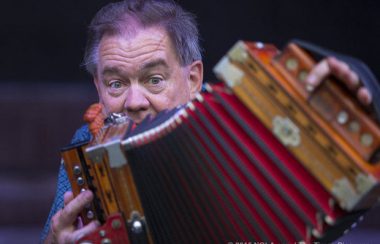 Le visage d'un homme en arrière d'un accordéon.