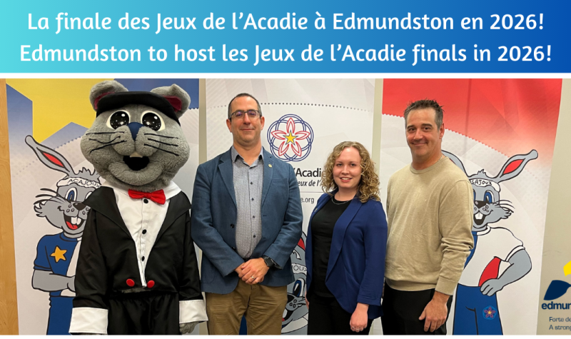 Trois personnes et une mascotte se trouvant devant une pancarte des Jeux de l'Acadie