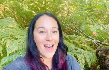 A smiling woman against a forest background