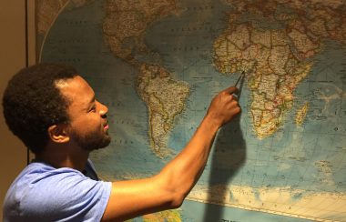 A man pointing at a spot on a map of the world