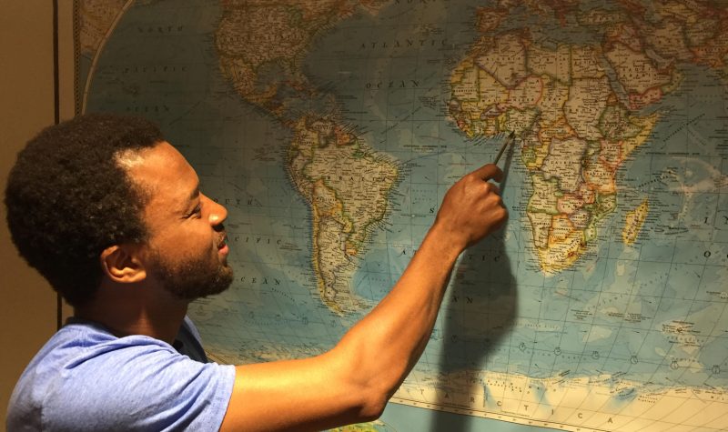 A man pointing at a spot on a map of the world