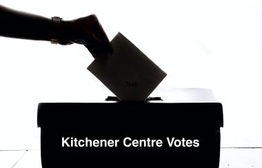 A black silhouette of a person placing a ballot in a box that reads in white lettering 'Kitchener Centre Votes'