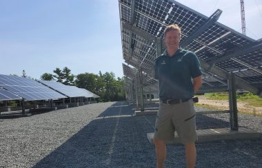 A man stands in front of a row of solar panels