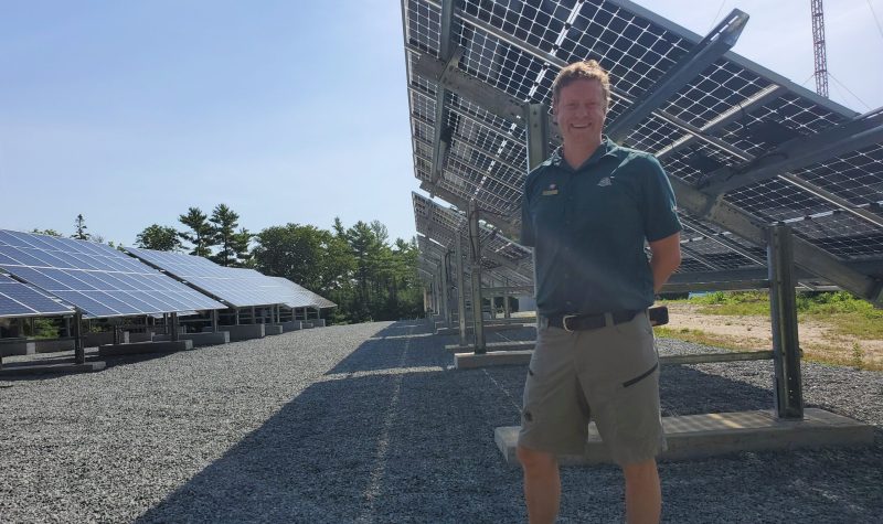 A man stands in front of a row of solar panels