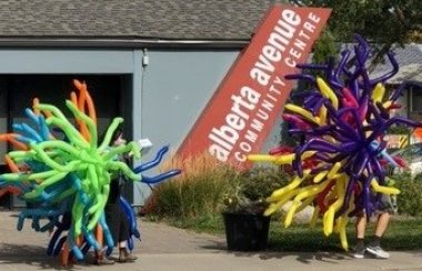 Two people dressed in colorful balloons walking on Alberta Avenue for Kaleido Festival