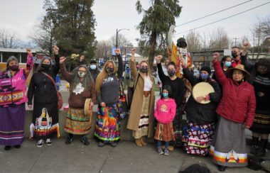 An outdoor group photo in Vancouver of Elder and organizer Kat Norris and other women gather at Grandview Park with ribbon skirts